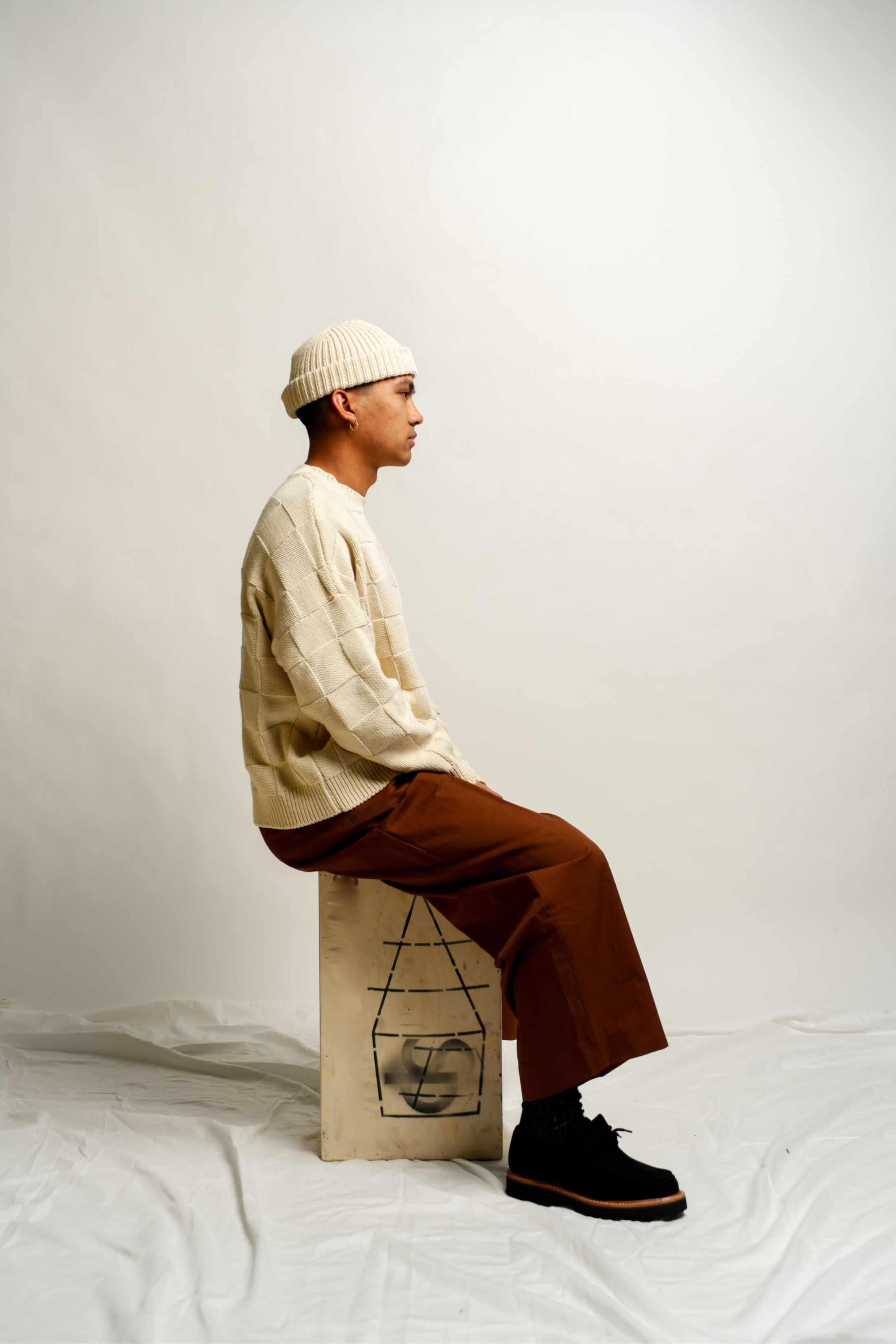 Man sitting with knitted sweater and beanie profile view